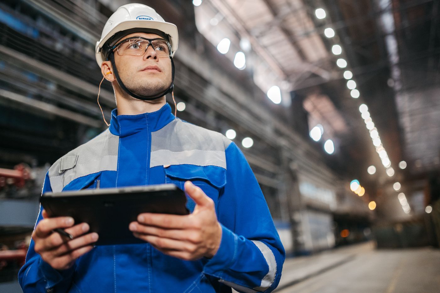 An engineer in a hard hat checking a tablet